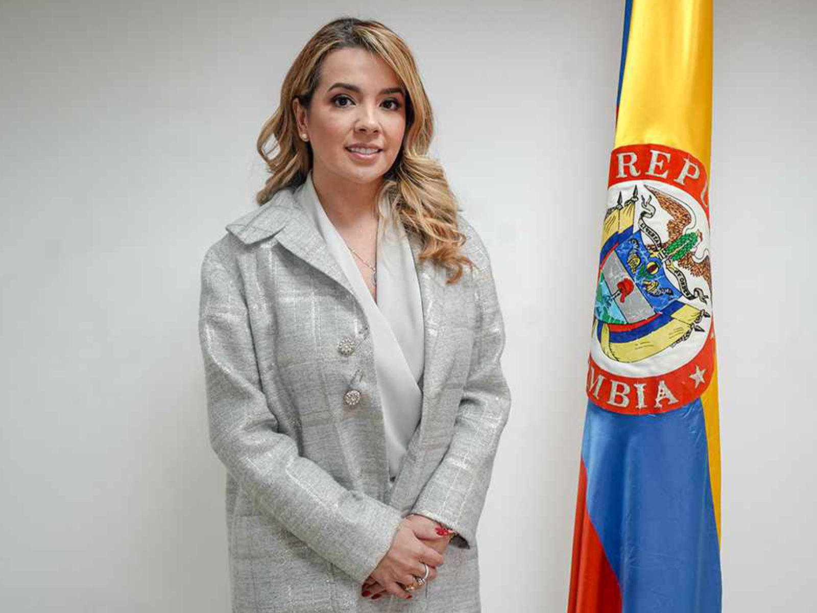 Sandra Viviana Cadena Martínez, superintendente del Subsidio Familiar, en retrato oficial junto a la bandera de Colombia